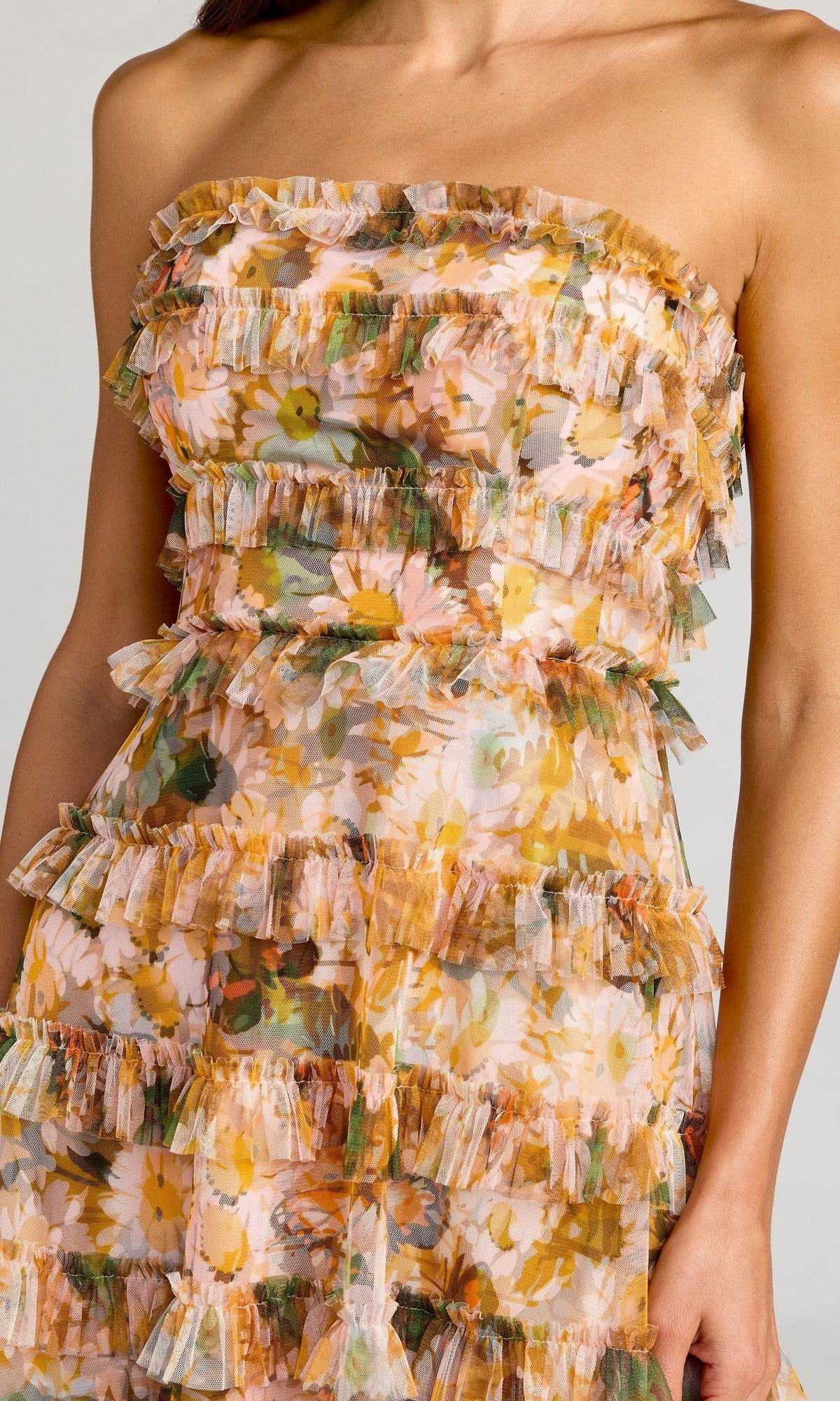 A person wearing the Mac Duggal 8137 Strapless Long Print Formal Dress, featuring ruffled tiers and a pastel floral design.